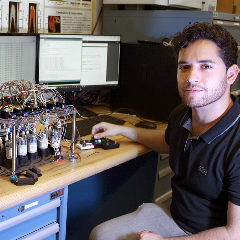 man sitting at desk and computer with some scientific equipment next to that
